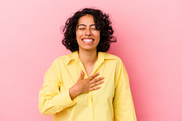 Young curly latin woman isolated on pink background laughs out loudly keeping hand on chest.