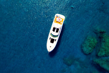 Top down view of white-yellow cruise boat on a blue water