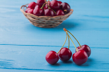 Composition of fresh ripe red cherries on blue desk background.
