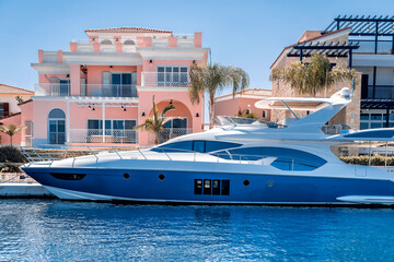 Luxury sea yacht parked near pink house in marina.