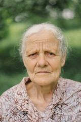 Portrait of a gray-haired adult grandmother against the background of nature.
