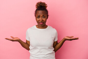 Young african american woman isolated on pink background doubting and shrugging shoulders in...