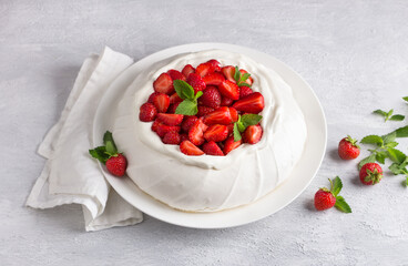 Classic Pavlova meringue cake with whipped cream and strawberries, sprinkled with powdered sugar on light gray textured background