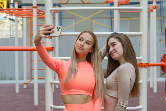 Two sporty young sexy women posing while taking selphy on the summer playground. Healthy lifestyle concept