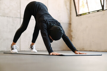 Young muslim woman in hijab doing exercise during yoga practice