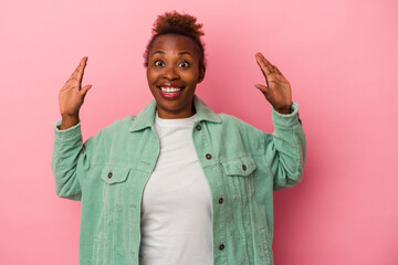 Young african american woman isolated on pink background receiving a pleasant surprise, excited and...