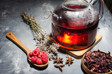 tea leaves, raspberries and tea in a glass teapot