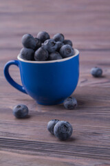 Pile of blueberries in a ceramic blue cup vertical shot.