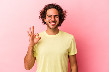 Young caucasian man isolated on pink bakcground cheerful and confident showing ok gesture.