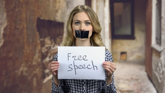 Young woman with mouth and lips sealed with black tape.