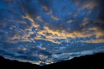 mountain scenery silhouette blue sky Yellow-orange clouds after sunset and after rain, evening. Beautiful evening sky image for the blue background.