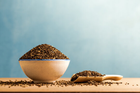 Syrian rue - peganum harmala seeds - in a bowl with scattered seeds on table. Copy space. Peganum harmala contains MAO-inhibiting (MAOI) substances. Also known as harmal seeds.