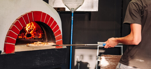 chef takes pizza. Italian pizza is cooked in a wood-fired oven