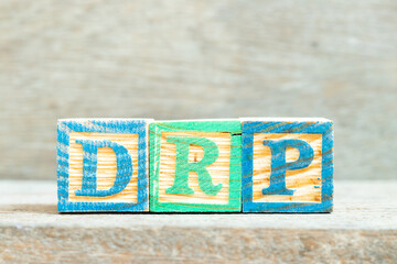 Color alphabet letter block in word DRP on wood background