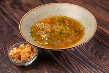Deep plate noodle soup with croutons, yellow chicken broth