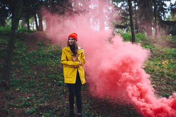 Smiling woman near smoke bomb in forest
