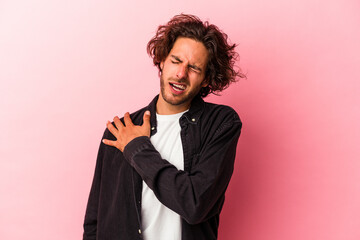 Young caucasian man isolated on pink bakcground having a shoulder pain.