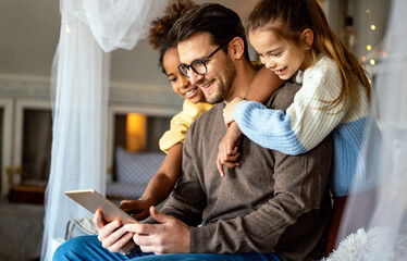 Happy father with multiethnic children playing with digital tablet at home