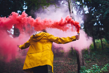 Unrecognizable woman with colorful smoke bomb
