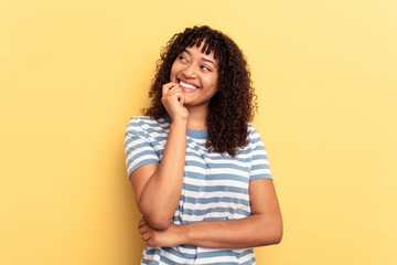 Young mixed race woman isolated on yellow background relaxed thinking about something looking at a copy space.