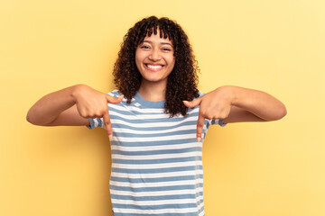 Young mixed race woman isolated on yellow background points down with fingers, positive feeling.