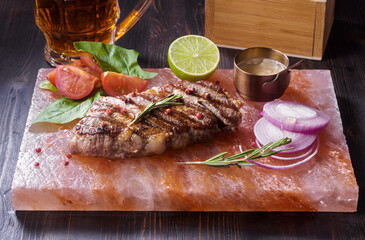 Grilled pork steak with rosemary, vegetables and lime served on himalayan salt tile - obrazy, fototapety, plakaty