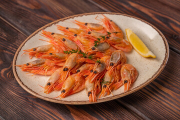 Beautifully laid out boiled tiger prawns on a plate with lemon slices and spices