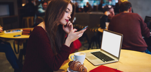 Serious woman looking at smartphone screen in cafe