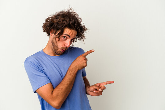 Young caucasian man isolated on white background pointing with forefingers to a copy space, expressing excitement and desire.