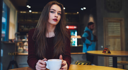 Calm woman drinking coffee in cafeteria