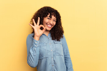 Young mixed race woman isolated on yellow background cheerful and confident showing ok gesture.