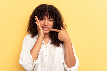 Young mixed race woman isolated on yellow background having a strong teeth pain, molar ache.