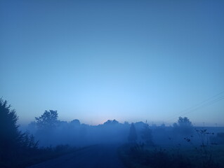 Fototapeta premium Thick autumn fog rises at sunrise over the Ukrainian village