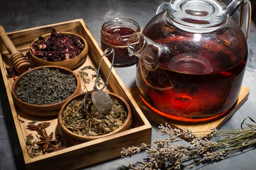 Dry tea leaves, raspberries and tea in a glass teapot