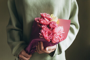 A woman holds a bouquet of pink tulips in her hands. The concept of a gift for Mother's Day, March 8 and other holidays