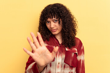 Young mixed race woman isolated on yellow background rejecting someone showing a gesture of disgust.