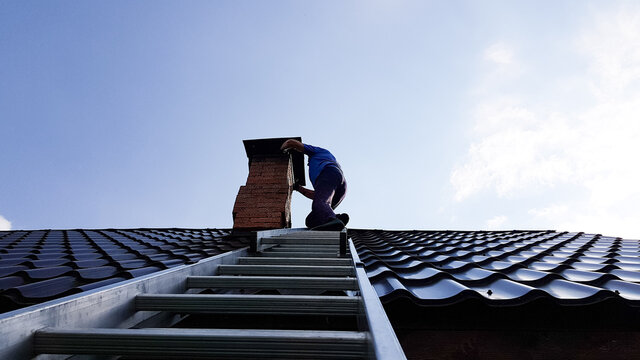 a chimney sweep climbs a metal ladder to the roof of the bathhouse to clean the pipe from burning