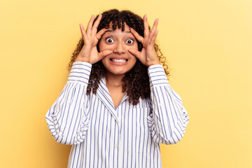 Young mixed race woman isolated on yellow background keeping eyes opened to find a success opportunity.