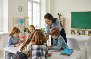 Young caucasian teacher teaching schoolchildren or preschooler group in classroom talking and...