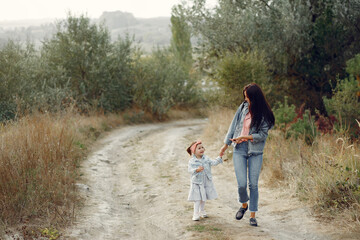 Mother with little daughter playing in a autumn field