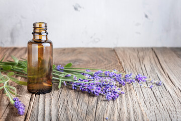 Obraz na płótnie Canvas Aromatherapy and essential oil, herbal natural cosmetics, alternative medicine and phytotherapy concept. Bunch of lavender flowers and glass bottle on wooden background