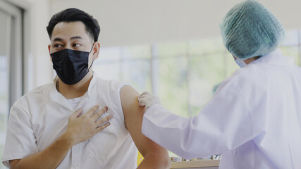 COVID-19 Vaccination station. Doctor or nurse are vaccinating man patient protect COVID-19 or flu...