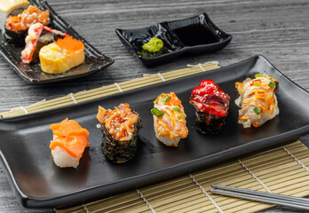 Japanese sushi set and with  shoyu soy sauce with wasabi in ceramic plate dark Placed on the table concrete grunge texture background., front view