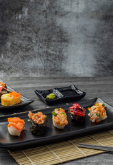Japanese sushi set and with  shoyu soy sauce with wasabi in ceramic plate dark Placed on the table concrete grunge texture background., front view