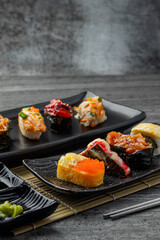 Japanese sushi set and with  shoyu soy sauce with wasabi in ceramic plate dark Placed on the table concrete grunge texture background., front view