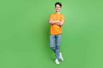 Fototapeta na wymiar Full size photo of charming young man hold hands crossed confident smile isolated on green color background