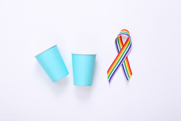 Paper cups with LGBT rainbow ribbon pride tape symbol on white background. Top view