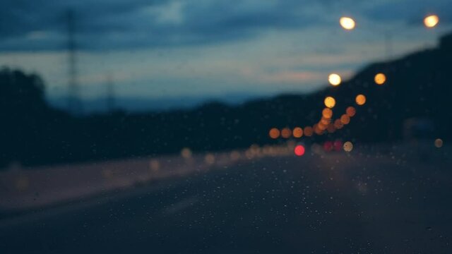 Colorful light night road, Rain drops on the window, storm raining driving with blur focus, Handheld camera concept.