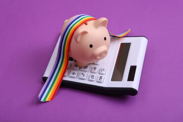 Calculator with piggy bank and LGBT rainbow ribbon pride tape symbol on blue background