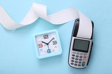 Pos terminal and alarm clock on blue background.